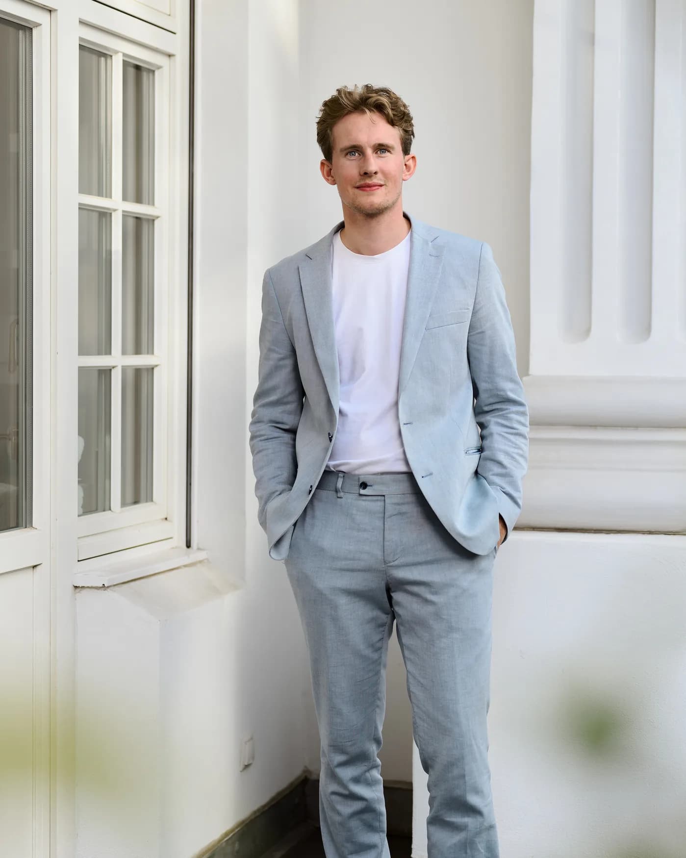Fabian Tiedemann im hellen Anzug vor einer weißen Altbaufassade
